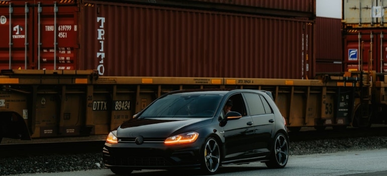 a black car in front of some containers