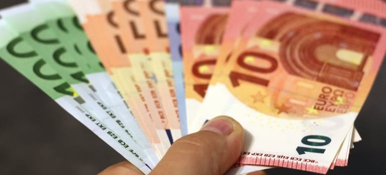 Person holding euros in their hand, Costs to Consider When Moving Abroad