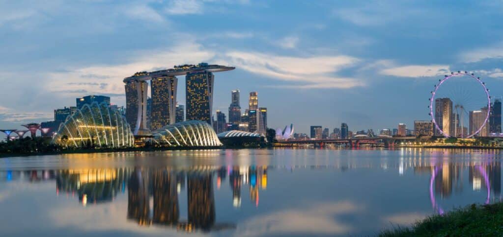 Scenic view of Singapore's skyline featuring Marina Bay Sands, futuristic architecture, and the Singapore Flyer at dusk, reflecting on the calm water, symbolizing the dynamic lifestyle awaiting those moving to Singapore.