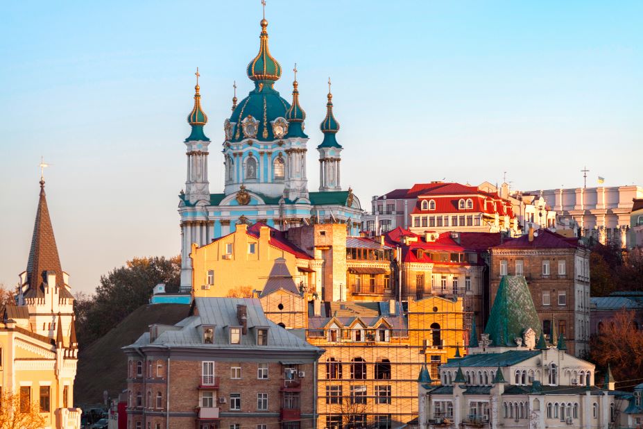 A picturesque view of colorful buildings with ornate roofs in Ukraine, featuring a prominent church with a turquoise dome.