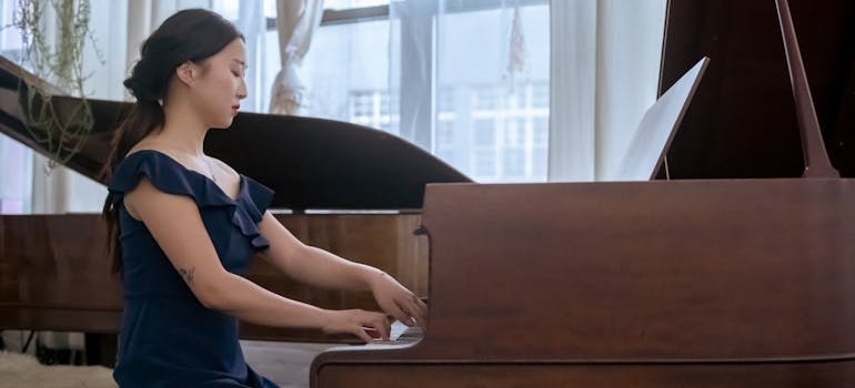 a woman playing a piano shipped by international piano movers