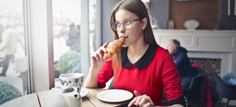 a girl eating a croissant in a cafe 