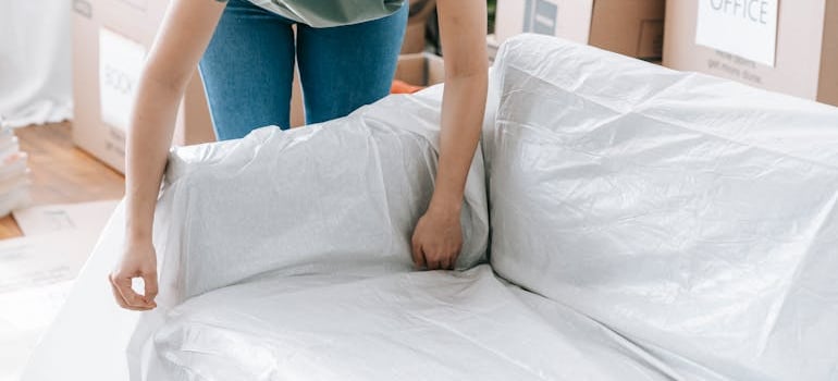 a person putting a moving blanket over the furniture