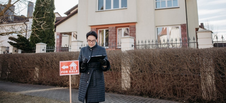 a woman standing in front of the house that is for sale 